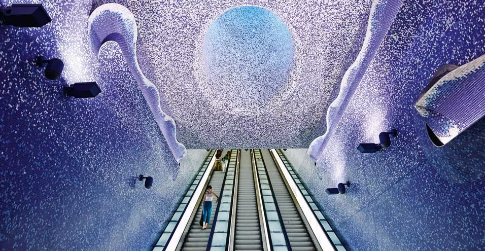 Una foto che ritrae l'interno della Stazione di Via Toledo a Napoli che ritrae la scala mobile e il cielo stellato su sfondo blu